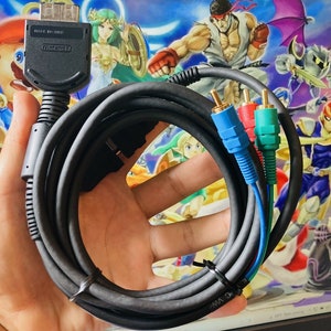 May include: A black Nintendo AV component cable featuring a proprietary console connector with the text MADE IN CHINA and Nintendo embossed on the housing. The cable includes three colour-coded RCA plugs in blue, red, and green for video output.