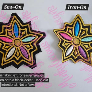 Puede incluir: Dos parches bordados en forma de estrella con un dise&ntilde;o floral. Uno est&aacute; etiquetado como "Sew-On" y el otro como "Iron-On". Los parches presentan un fondo negro con ribete dorado y detalles florales coloridos en rosa, azul y blanco. El texto dice: "Exceso de tela para facilitar la costura en una chaqueta negra. Cortado a mano. Intencional. No es un defecto."