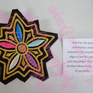 Puede incluir: Parche negro en forma de estrella con un dise&ntilde;o floral. El parche presenta bordados dorados, rosas, azules y blancos. El texto en la tarjeta dice: "Sew-On: For your convenience, extra material is left around the edges to sew the patch onto the project."