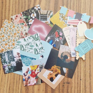 K&ouml;nnte beinhalten: Eine Sammlung von buntem Scrapbook-Papier, Aufklebern und Ephemera, darunter Blumenmuster, ein Pinguin, eine Wolke und ein Ticket mit der Aufschrift "ADMIT ONE".