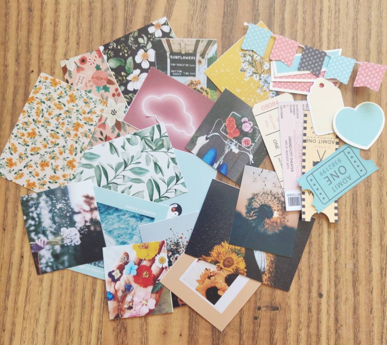K&ouml;nnte beinhalten: Eine Sammlung von buntem Scrapbook-Papier, Aufklebern und Ephemera, darunter Blumenmuster, ein Pinguin, eine Wolke und ein Ticket mit der Aufschrift "ADMIT ONE".