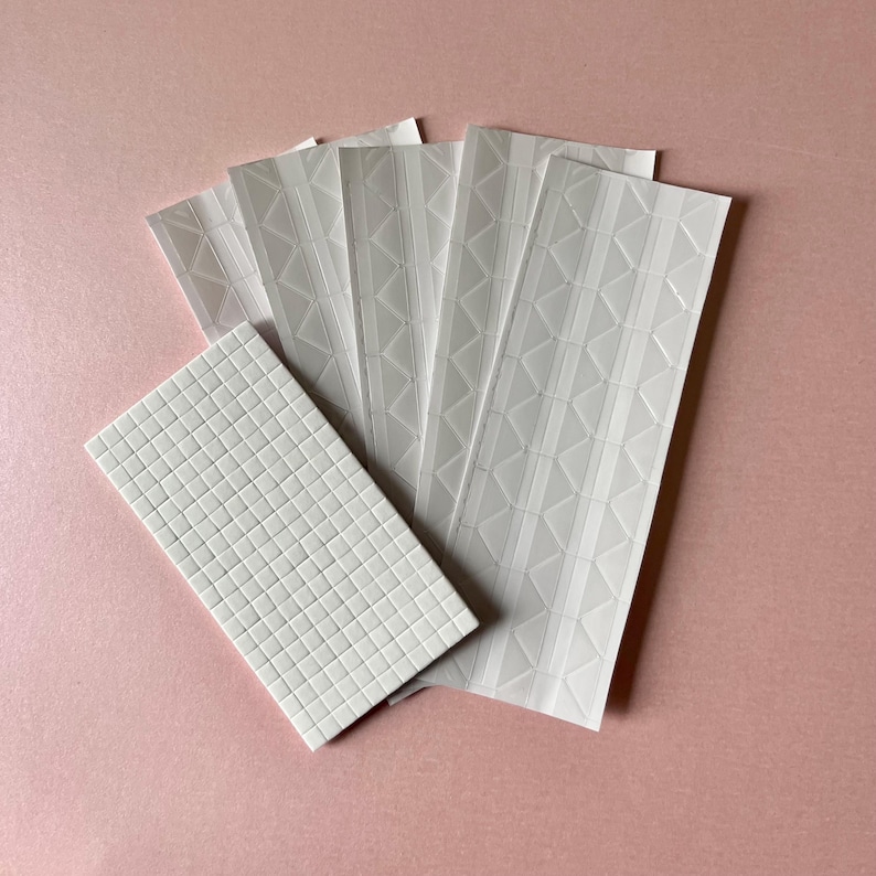 May include: A collection of white adhesive sheets featuring embossed patterns. One sheet displays a dense grid of small squares, while the other four sheets show a repeating geometric design of vertical lines and triangles in a raised texture.