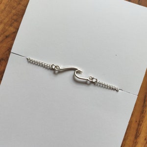 May include: A silver chain bracelet with a wave-shaped charm.