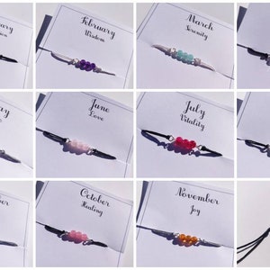 May include: Twelve cards with the months of the year and a corresponding word, each with a bracelet featuring different coloured beads.