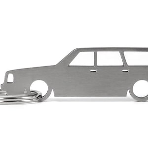 Könnte beinhalten: Ein silberner Schlüsselanhänger in Form eines alten Volvo Kombi. Der Schlüsselanhänger hat einen Ring zum Anbringen von Schlüsseln.