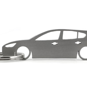Op de afbeelding: Een zilverkleurige autosleutelhanger. De sleutelhanger is een silhouet van een hatchback auto met een sleutelring eraan. De auto heeft twee deuren en een raam. De sleutelhanger is van metaal en staat op een witte achtergrond.