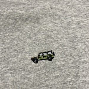May include: A grey t-shirt with an embroidered green jeep design.