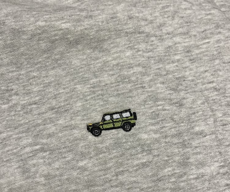 May include: A grey t-shirt with an embroidered green jeep design.
