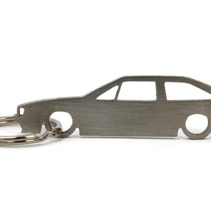 May include: A silver metal keychain shaped like a car. The keychain has a silver metal ring attached to it.