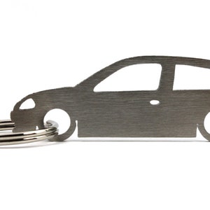 Può includere: Un portachiavi in metallo argentato a forma di auto. Il portachiavi ha un anello in metallo argentato.