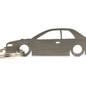 May include: A silver metal keychain shaped like a car. The keychain has a silver metal ring attached to it.