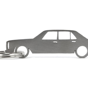 Può includere: Un portachiavi in metallo argentato a forma di auto d'epoca. Il portachiavi ha un anello per le chiavi attaccato alla parte inferiore.