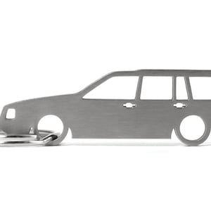 Könnte beinhalten: Ein silberner Schlüsselanhänger in Form eines Volvo Kombi. Der Schlüsselanhänger hat einen Ring zum Anbringen von Schlüsseln.