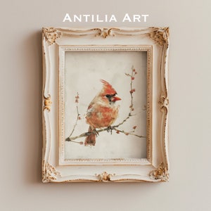 Könnte beinhalten: Ein gerahmtes Aquarellbild eines roten Kardinals, der auf einem Zweig mit zarten rosa Blüten sitzt. Der Vogel ist nach rechts gewandt und hat eine detaillierte, realistische Darstellung. Der Rahmen ist weiß mit verzierten Details.