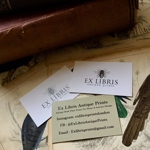 May include: An assortment of antique prints and ephemera. The image features a vintage book, several business cards with the text "EX LIBRIS antique prints", and a detailed illustration of a bird. The business cards also include contact information.