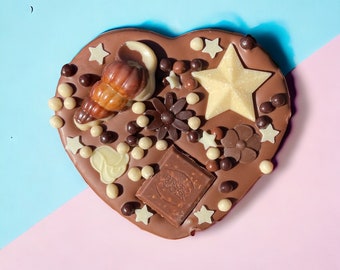May include: A heart-shaped chocolate bar with a variety of toppings, including chocolate stars, seashells, and chocolate sprinkles. The bar is decorated with the words "Ferrero Rocher".