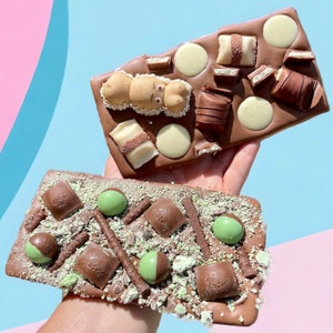 May include: Two chocolate bars, one with a green mint and chocolate design and the other with white chocolate, milk chocolate, and a chocolate bunny.