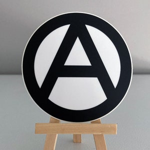 May include: A black and white anarchy symbol sticker on a small wooden easel.