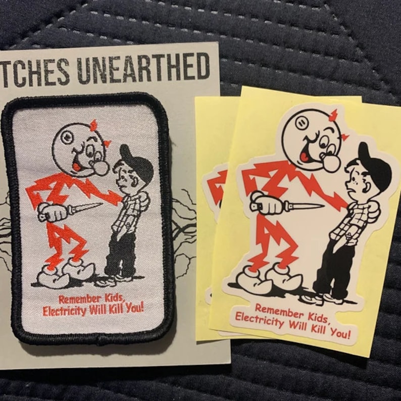 May include: A red and white patch with a cartoon character holding a knife and the text "Remember Kids, Electricity Will Kill You!" Two yellow stickers with the same image and text are also shown.