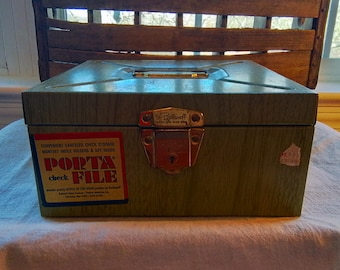 May include: A green metal check file box with a lock and key. The box has a wood grain pattern and the text "Porta Check File" on the front.