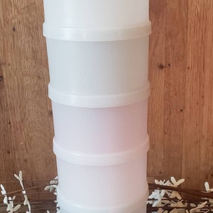 May include: A white plastic stackable container with five sections. The container is made of clear plastic and has a smooth finish.