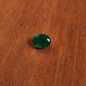 May include: A round, green glass cabochon with a slightly textured surface.