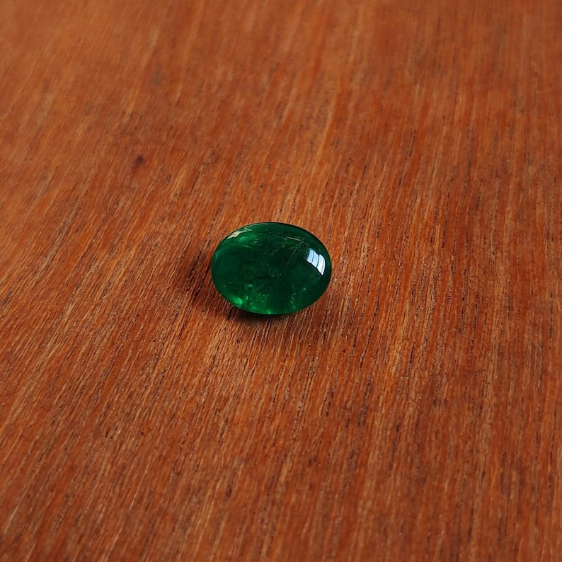 May include: A round, green glass cabochon with a slightly textured surface.