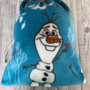 May include: A blue fleece drawstring bag with a white and orange Olaf character from the movie Frozen. The bag has a white drawstring.