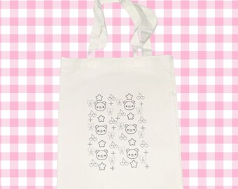 May include: A white canvas tote bag with a repeating pattern of black and white illustrations of bears, stars, cherries, and bows.