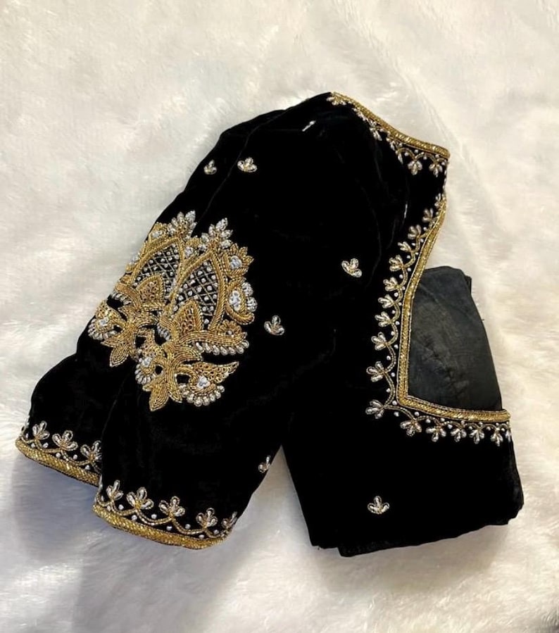 May include: A black velvet blouse with gold and silver embroidery. The blouse has a high neckline and long sleeves.