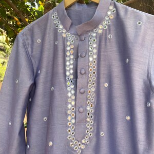 K&ouml;nnte beinhalten: Eine hellblaue Kurta mit einem silbernen Spiegel-Design. Die Kurta hat einen Mandarinkragen und einen Knopfverschluss.
