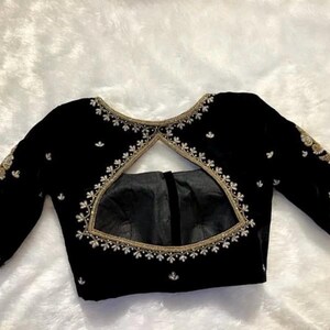 May include: A black velvet blouse with a keyhole back and gold and white embroidery.