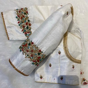 May include: White silk blouse with gold and silver embroidery. The embroidery features floral designs with red, green, and blue accents.