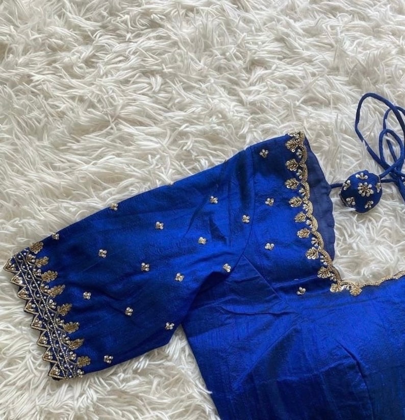 May include: A royal blue silk blouse with gold and silver embroidery. The blouse has a scalloped neckline and short sleeves.