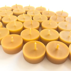 Puede incluir: Un grupo de 30 pequeñas velas de té redondas de color miel de cera de abeja.