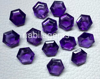 Könnte beinhalten: Eine Sammlung facettierter, sechseckiger Amethyst-Edelsteine. Die Edelsteine haben eine tiefviolette Farbe und sind auf einer hellen Oberfläche angeordnet. Der Text "nabilagems" ist im Bild zu sehen.