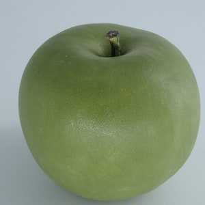 Könnte beinhalten: Ein grüner Apfel mit braunem Stiel und einer glatten, glänzenden Oberfläche.