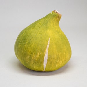 Può includere: Un fico in ceramica verde con una striscia bianca sul lato. Il fico è liscio e ha una finitura lucida.