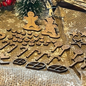 Pu&ograve; includere: Una collezione di addobbi natalizi in legno, tra cui omini di pan di zenzero, bastoncini di zucchero, stelle e una ciambella. Gli addobbi sono dipinti di marrone e hanno un aspetto rustico.