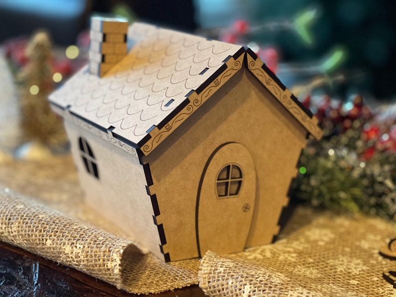 Pu&ograve; includere: Una piccola casa di legno con un tetto marrone e un camino. La casa ha una porta e una finestra. La casa &egrave; decorata con un motivo floreale.