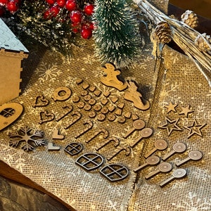 May include: A wooden gingerbread house kit with various cut-out pieces, including windows, stars, candy canes, and a snowman. The pieces are arranged on a burlap surface with a small pine tree and red berries.