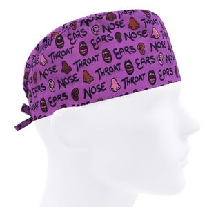 May include: Purple surgical scrub hat with a repeating pattern of cartoon ears, noses, and mouths with the words "ears", "nose", and "throat" printed on it.