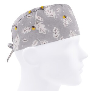 Puede incluir:  gorro de quirófano gris con un patrón de hojas de roble y bellotas blancas y marrones.