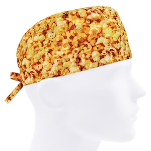May include: A white scrub hat with a popcorn print. The hat has a tie on the side.