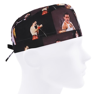 May include: Black surgical scrub cap featuring a repeating pattern of images of a singer on stage. The images are in shades of brown, red, and white. The cap has a tie in the back for an adjustable fit.