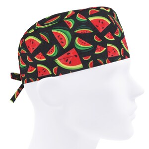 Puede incluir: Un gorro quirúrgico negro con un patrón repetido de rodajas de sandía rojas con cáscaras verdes. El gorro, con cierre de lazo, se muestra en una cabeza de maniquí blanca.
