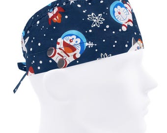 Könnte beinhalten: Blaue OP-Mütze mit weißem Hintergrund und einem sich wiederholenden Muster aus Comicfiguren, Sternen und Schneeflocken. Die Figuren tragen Astronautenanzüge.