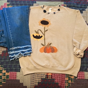 Fall Applique Sweatshirt of Sunflowers snuggled up to a pumpkin.