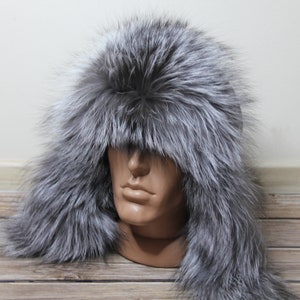 May include: A silver fox fur hat with ear flaps. The hat is made of soft, luxurious fur and is ideal for keeping warm in cold weather.