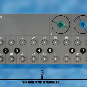 Puede incluir: Un sintetizador gris con el texto "OP-Z" en la parte delantera. El sintetizador tiene una serie de botones y perillas, incluida una fila de botones numerados del 1 al 9. El sintetizador tiene 12,7 cm de ancho.